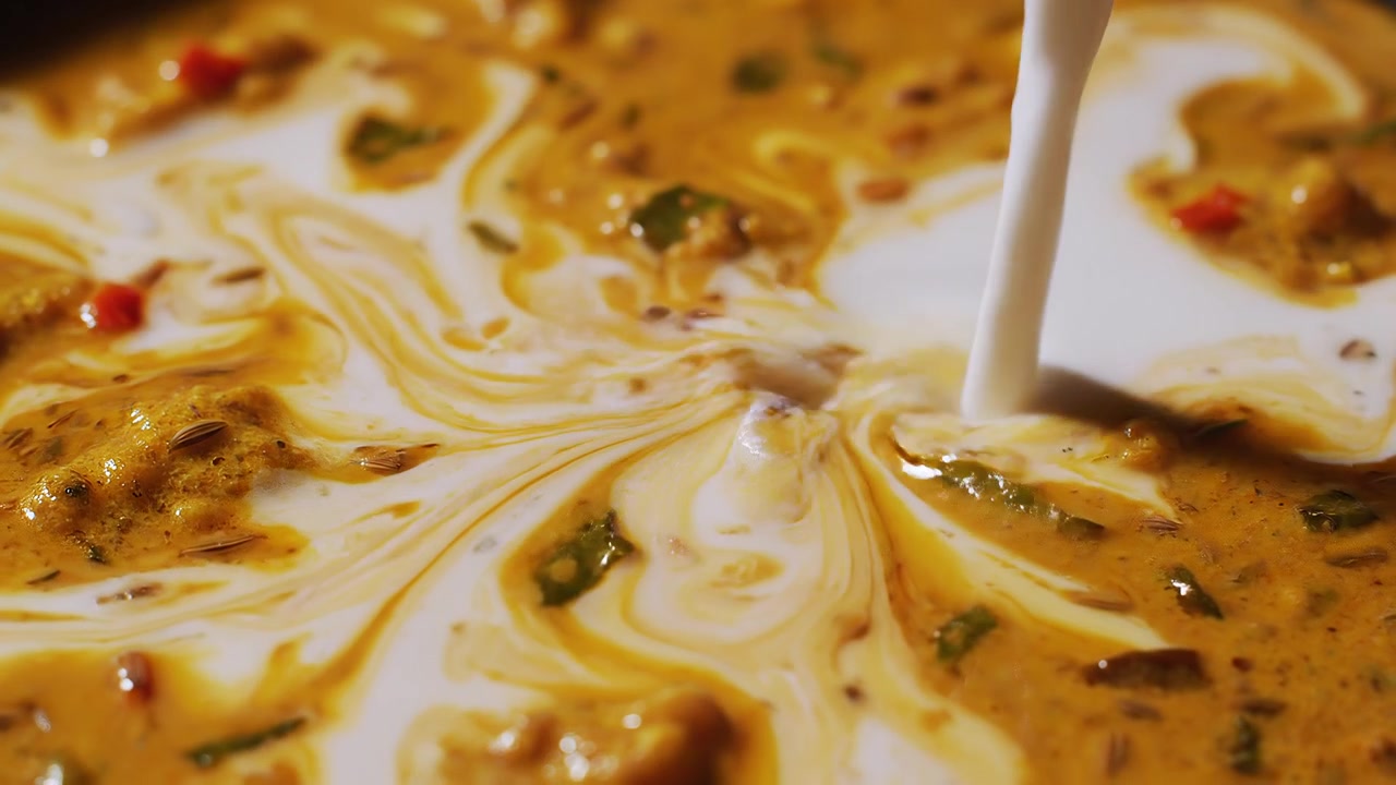 Slow Motion Pouring of Creamy Coconut Milk into Golden Curry