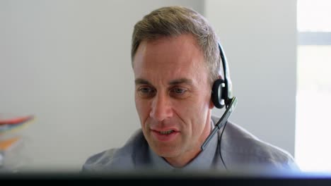 Businessman-talking-on-headset-while-working-on-computer-4k