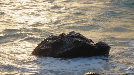 sunlit ocean waves breaking into stone during golden hour