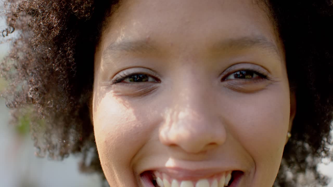 Female observing shifting light in garden foliage guiding gaze turning toward camera smiling warmly