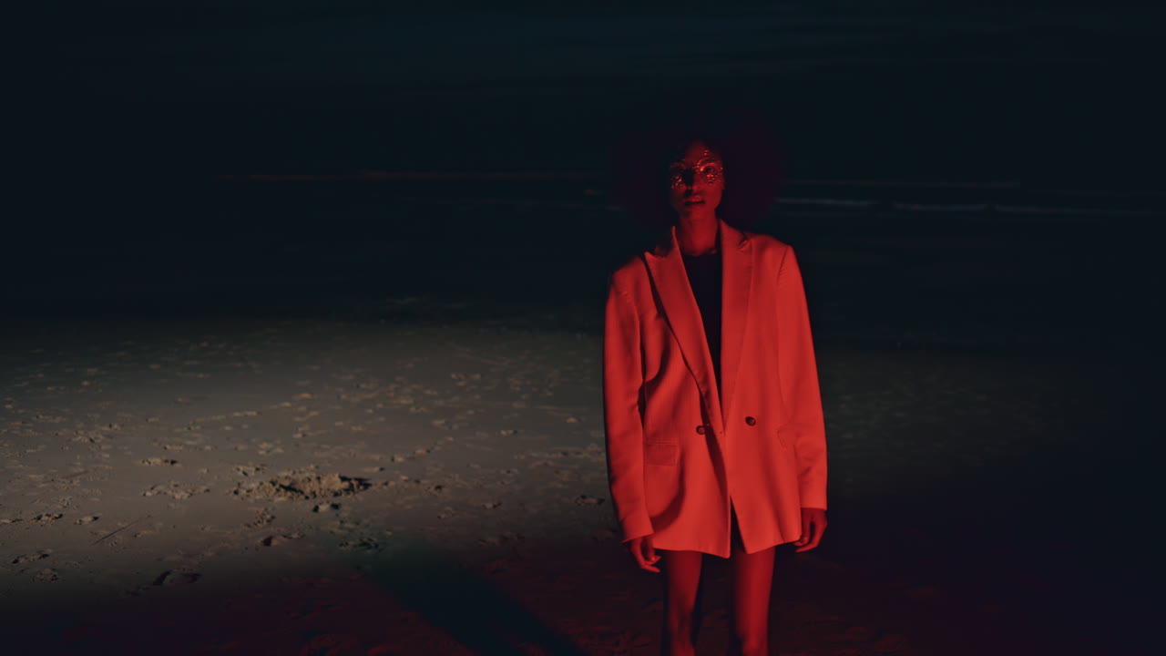 Woman walking night beach in pink light jacket. Slim sexy girl posing dark shore
