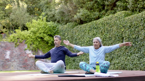 focused diverse senior couple practicing yoga meditation in garden