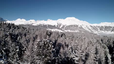 aerial view of snow covered mountain landscape with forests on a sunny day in switzerland