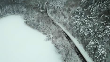 Road-in-snowy-forest-above-frozen-lake