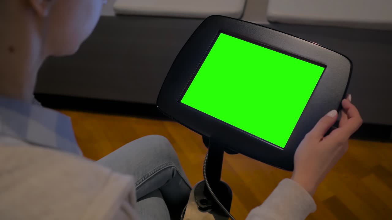 그린 스크린 컨셉 - 바닥에 서 있는 태블릿 키오스크의 디스플레이를 보는 여성