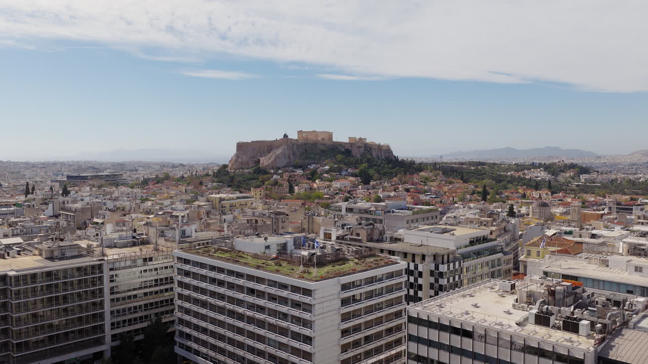 Lenta ripresa panoramica con drone dell'Acropoli e del Partenone di Atene in una giornata limpida con nuvole soffici nel cielo