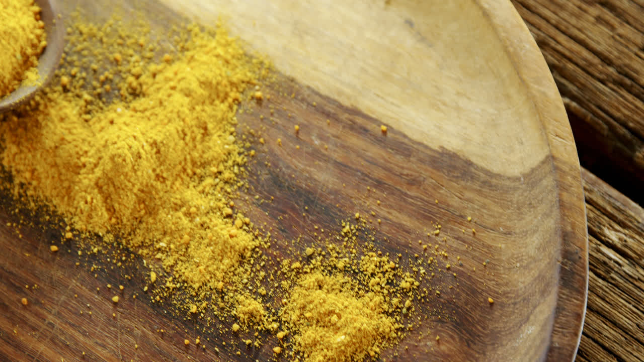 Curcuma in polvere in un cucchiaio su un piatto 4K