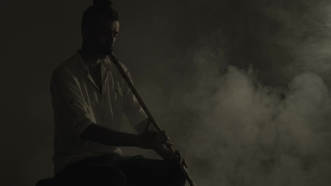 38 años de edad, flauta de caña del medio oriente o jugador de instrumento ney tocando una flauta de caña en el humo.