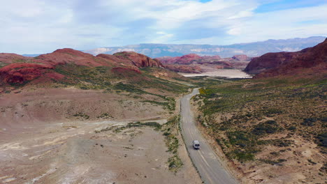 Toma-Aérea-De-Viajeros-Con-Un-Enorme-Paisaje-Desértico-De-Camiones-De-Expedición-En-La-Montaña-Polvorienta-De-Argentina-Al-Fondo.