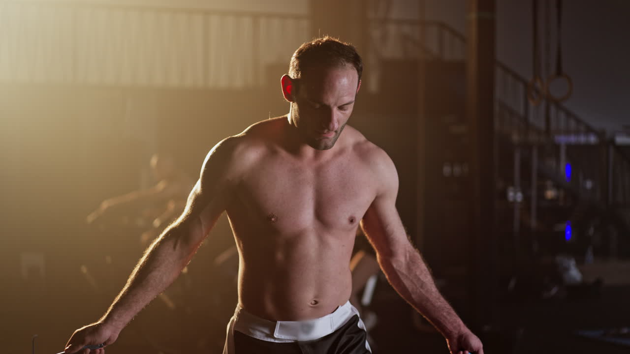 Shirtless man skipping rope in a gym