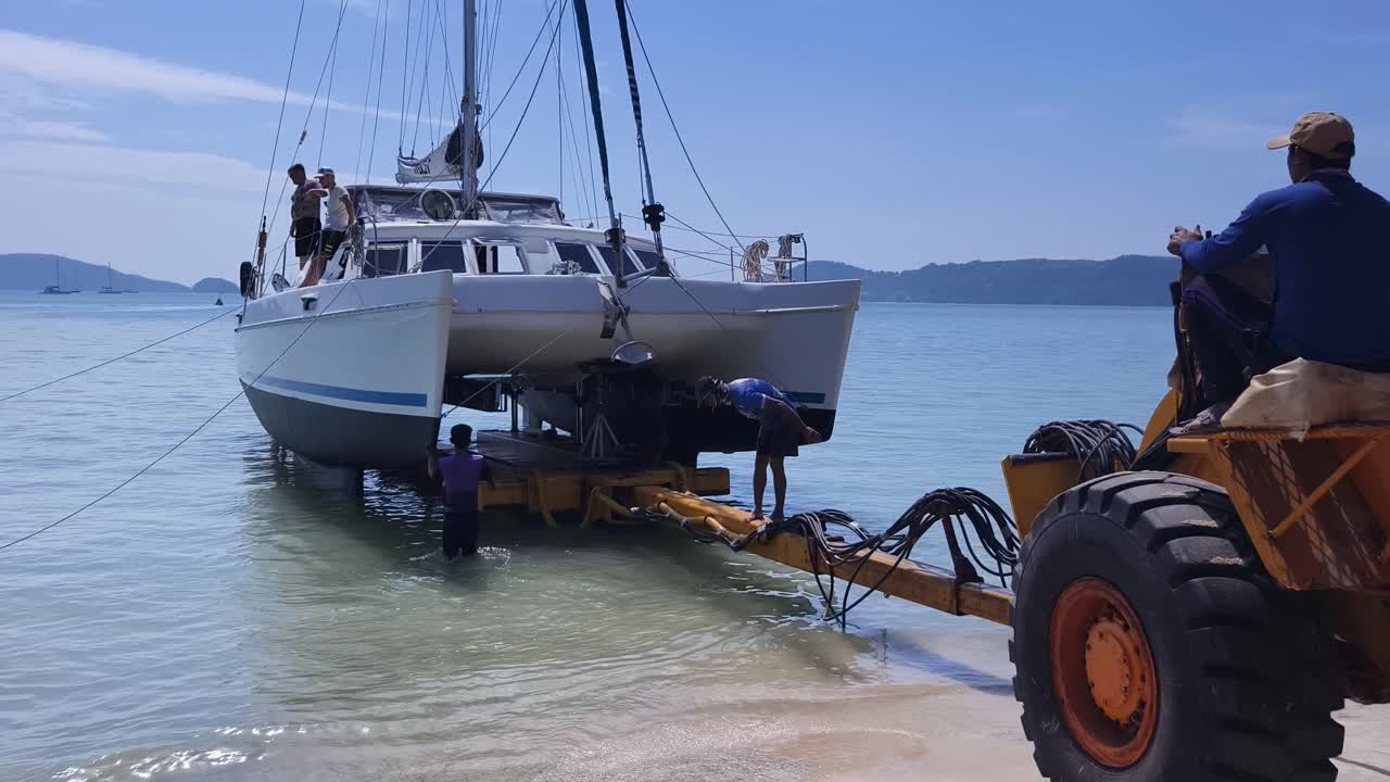 catamarán siendo transportado por un remolcador en la playa