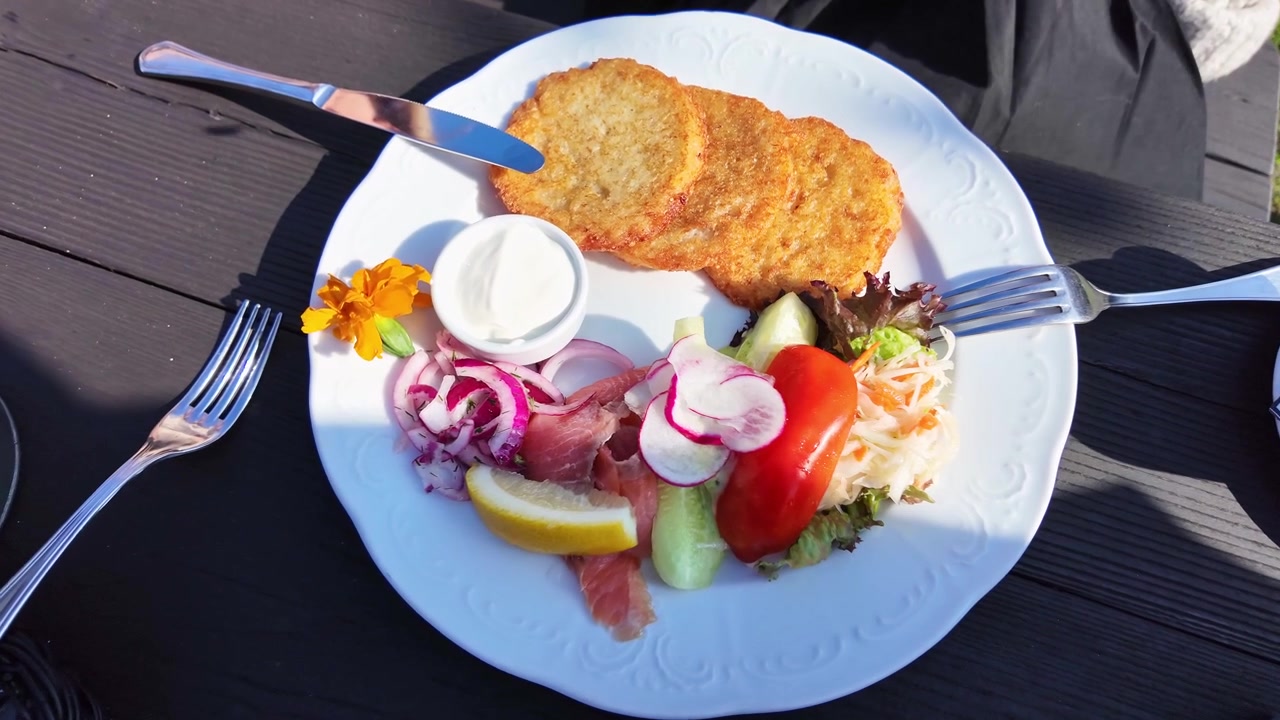 Gyldne kartoffelpandekager serveret med creme fraiche og frisk grøntsagstilbehør.