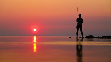 woman fishing on fishing rod spinning at sunset background.