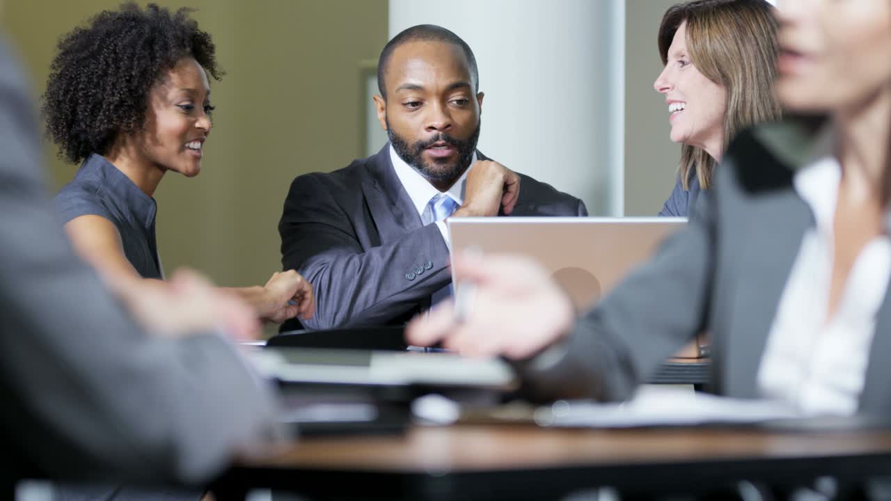 Multi ethnic business managers using laptop in meeting