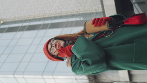 woman talking on phone outside, holding coffee