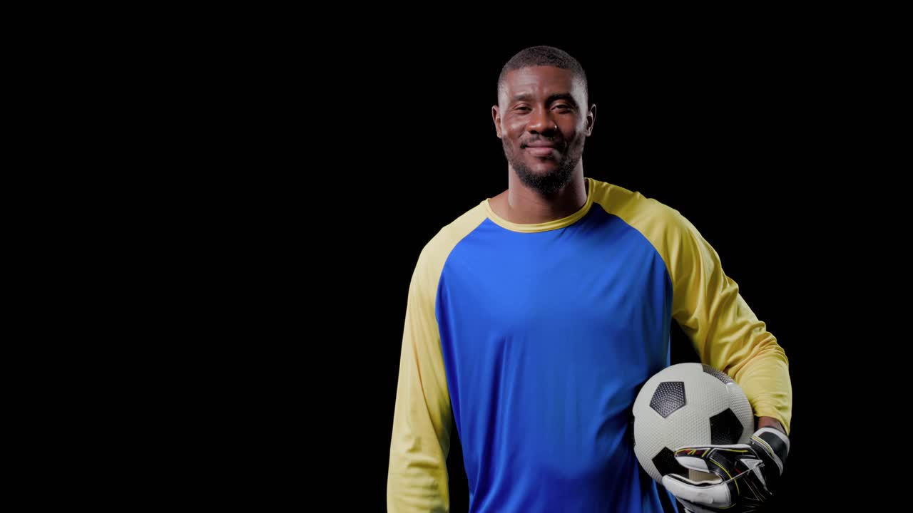 Portiere uomo che si allunga, tirando il pallone verso di sé, rilassando la postura mentre la telecamera stringe l'inquadratura per lo sport.