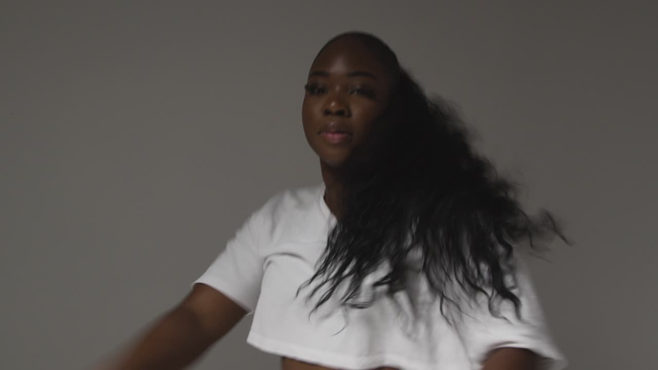 студийный портрет молодой женщины, танцующей при низком освещении на сером фоне