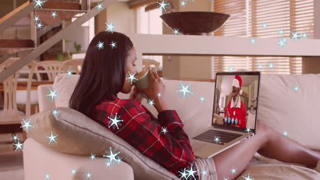 Animation-of-snow-falling-over-mixed-race-woman-on-laptop-video-call-with-santa-at-christmas