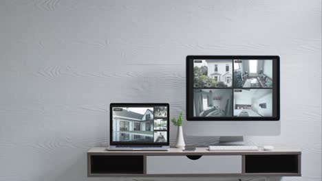 wall mounted computer monitor and laptop on desk with security camera views on screens, slow motion