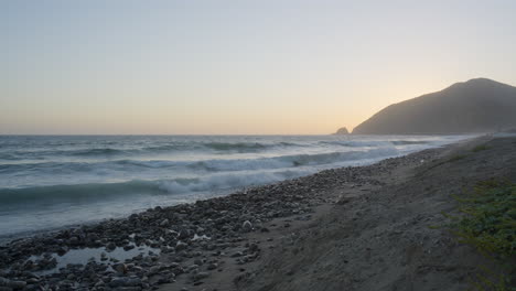 Vista-A-Nivel-De-La-Playa-De-Las-Olas-Rompiendo-En-Las-Orillas-De-La-Playa-De-Mondo-A-La-Hora-Dorada-Cuando-Sube-La-Marea-Ubicada-En-El-Sur-De-California,-Estados-Unidos