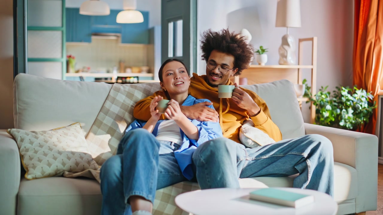 Kærligt par drikker kaffe på sofaen derhjemme. Nærbillede af afslappende weekend