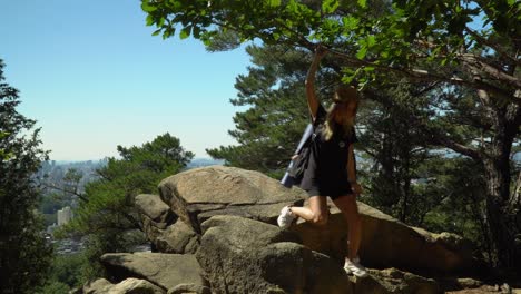 caucasian girl going down on the boulders after looking at the scenic landscape from gwanaksan mountain under the bright blue sky in seoul, south korea