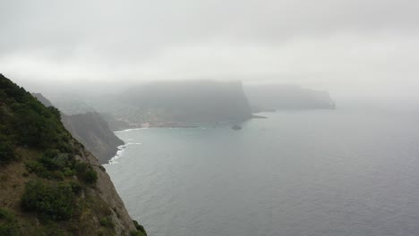 revealing aerial view, hills and misty coastline of madeira island, portugal, rainy clouds and skyline, drone shot