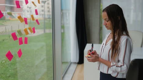 una mujer joven y hermosa haciendo notas en la ventana.