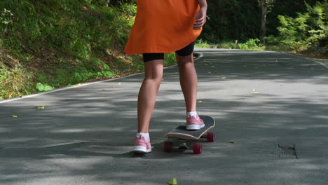 chica patinando en un camino en un bosque