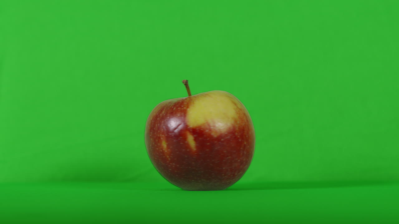 Frisk æble, der drejer rundt på grøn skærmbaggrund. Optagelser af sund plantebaseret vegansk vegetarisk mad, klar til keying. ProRes 4K