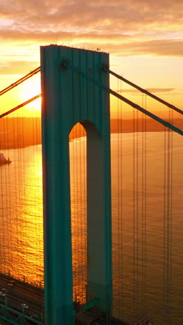 whitestone bridge in the rays of setting sun. cars going along the bridge back and forth. yachts and boats sailing along the east river. vertical video