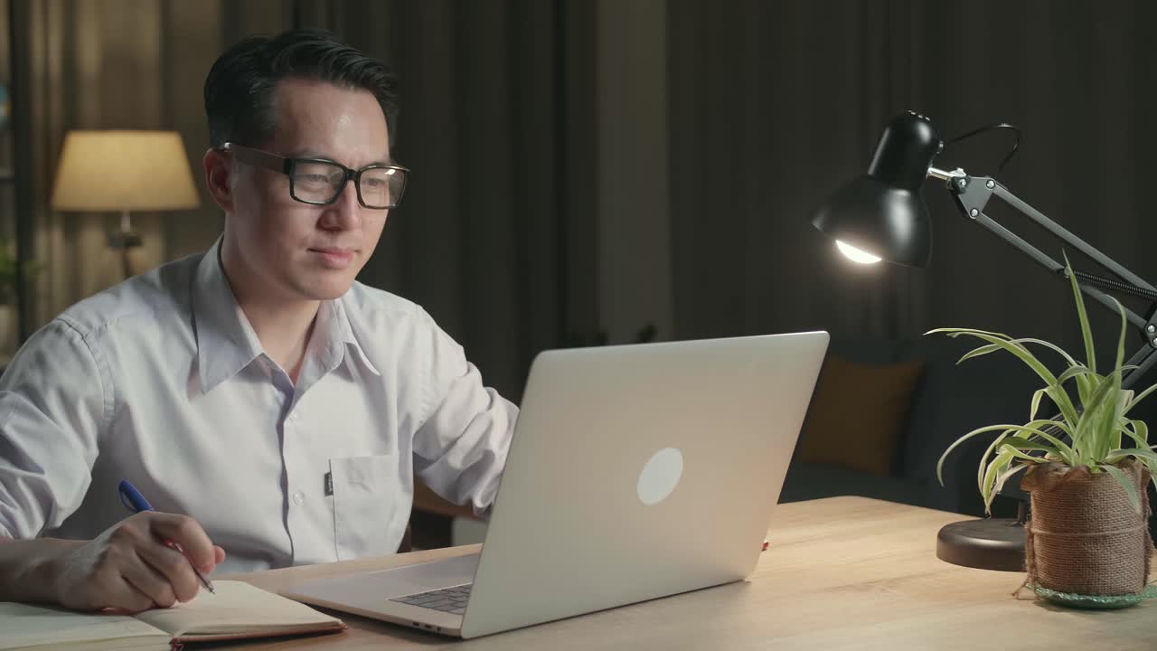 Man Working Late at Home on Laptop and Notebook