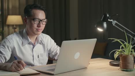 man working late at home on laptop and notebook