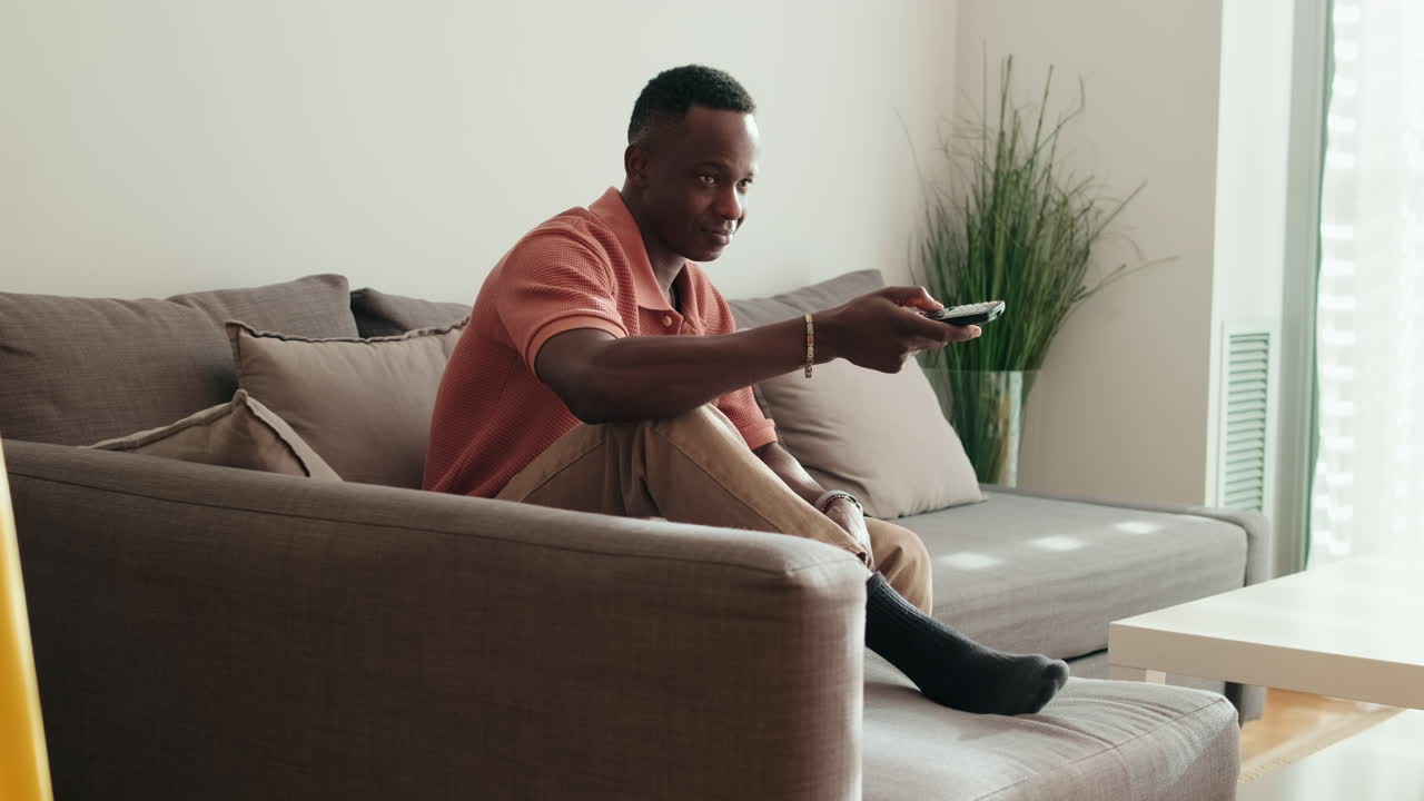 African American Man Relaxing on Sofa and Watching Television