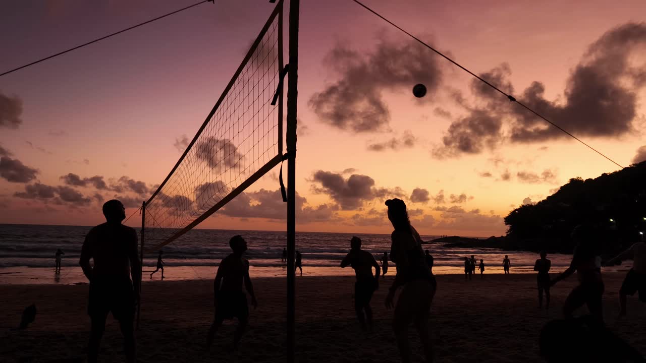 Beach volleyball game at sunset