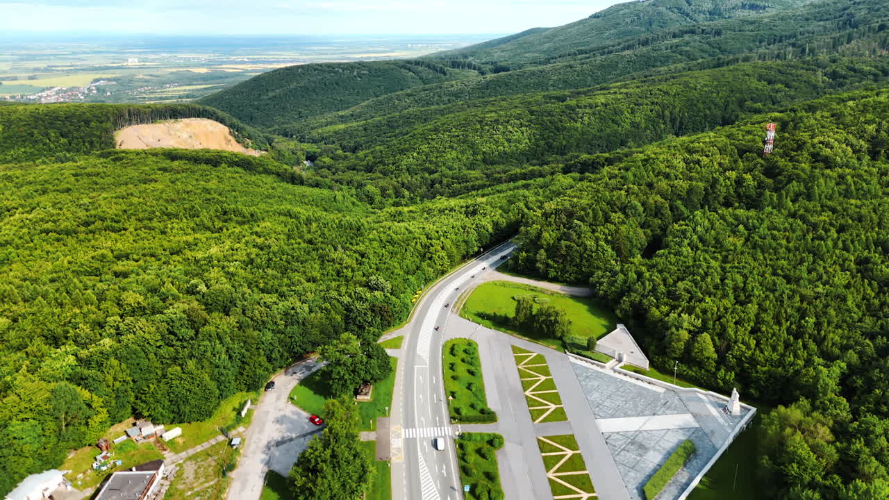 Aerial view of highway in forest. Aerial view showcases a highway cutting through lush green forest, with a modern structure visible nearby