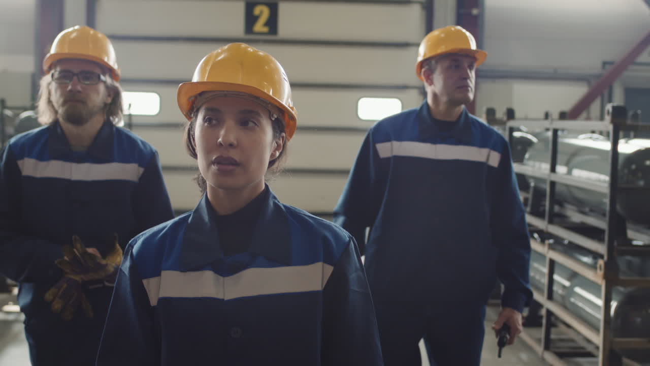 Tilt Up Of Female Supervisor With Workmen Walking Through Factory