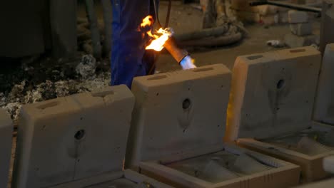 Mid-section-of-worker-heating-metal-mold-with-blow-torch-in-foundry-workshop-4k