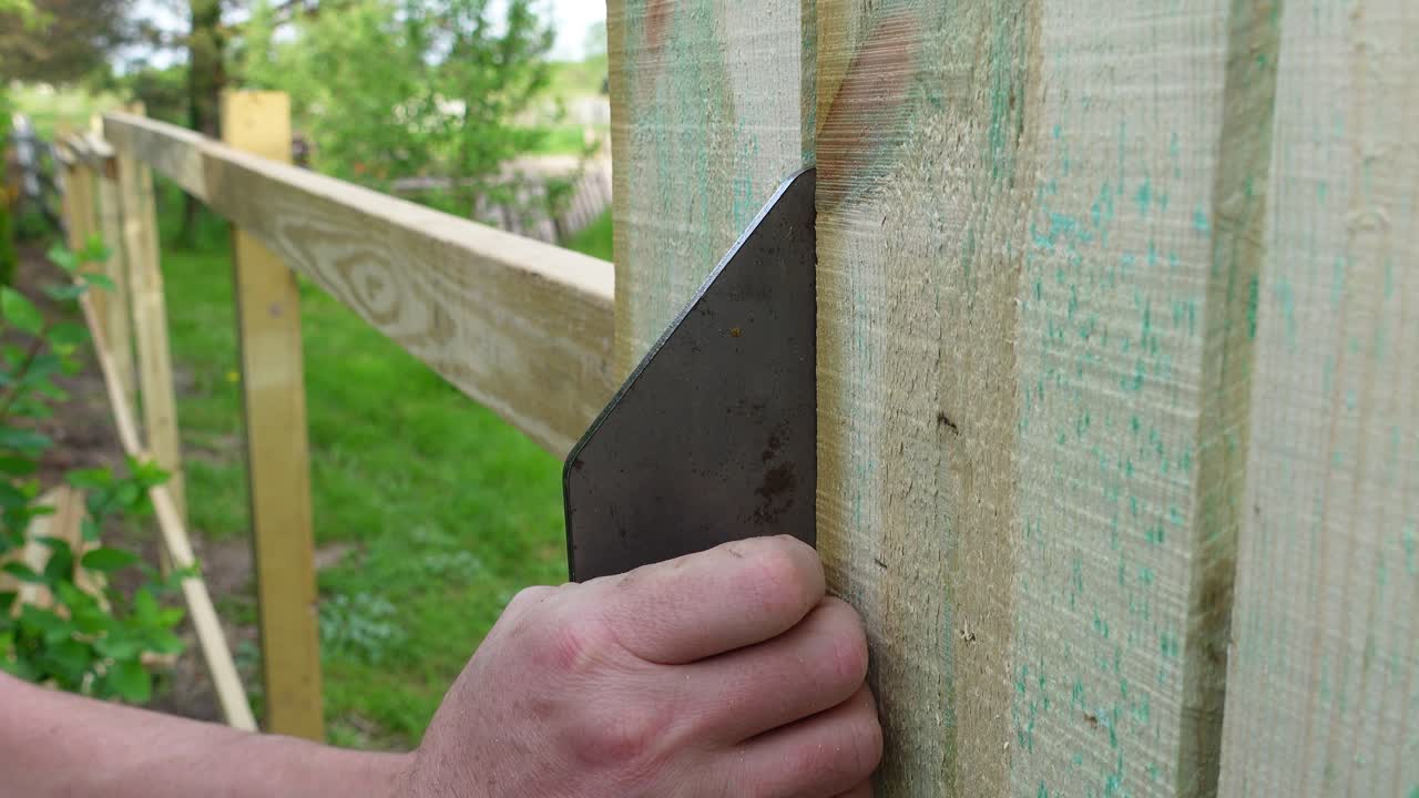 Person measuring fence plank and using pneumatic nail gun to build, close up