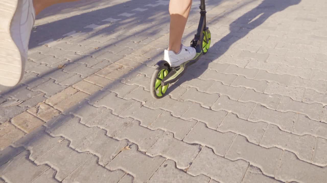 Male feet riding scooter in the city.