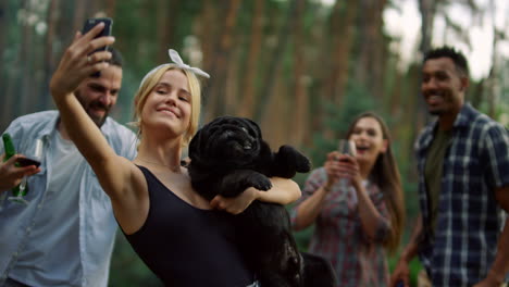 personas sonrientes divirtiéndose en una fiesta de barbacoa afuera. hombre bromeando mordiendo al perro al aire libre