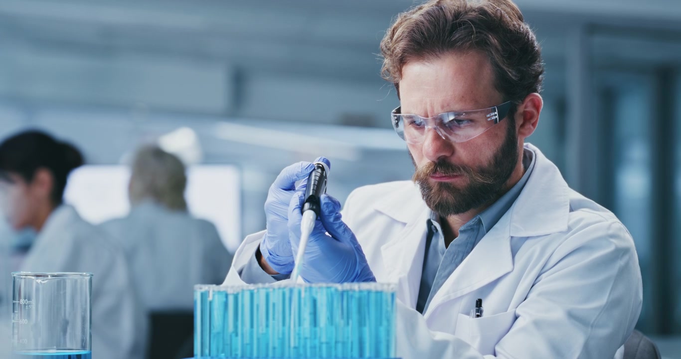 Scienziato che usa una pipetta per analizzare un liquido blu in laboratorio