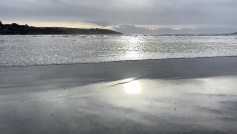 Zeitlupenwelle,-Die-Sich-Im-Winter-An-Einem-Sandstrand-Mit-Sonnenblendung-über-Der-Oberfläche-Bewegt