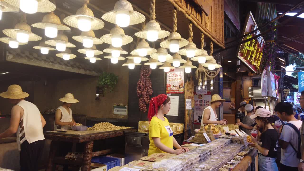Xian, China -  July 2019 :  Two men hitting hard with big wooden hammers to crack grain which will be used in making of sweet snack for sale on the street, Muslim Quarter