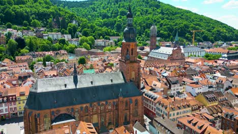 4k aerial drone video of the historic heiliggeistkirche and jesuitenkirche churches along the neckar river in heidelberg, germany