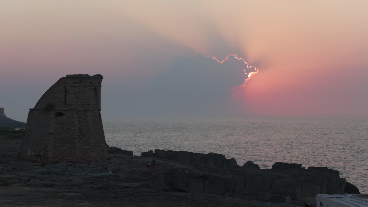 Watchtower at Porto Miggiano, Puglia, dramatic sunrise with sun rays over calm sea, Italy. Aerial drone