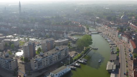 Toma-Aérea-De-Un-Velero-Navegando-Por-La-Histórica-Ciudad-De-Middelburg,-Países-Bajos,-En-Una-Soleada-Tarde-De-Verano