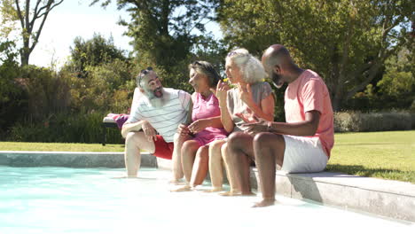 sitting by pool, senior friends laughing and enjoying sunny day together, copy space