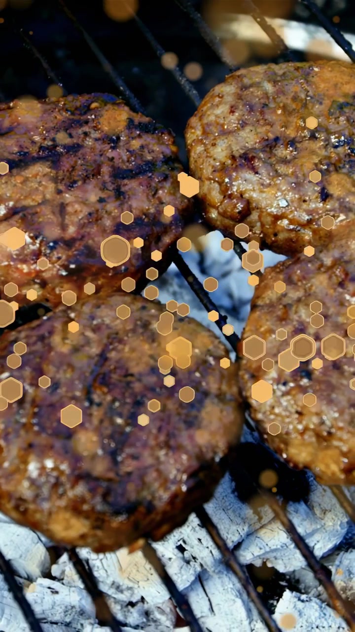 Vertical video: Glowing coals starting four patties searing, fat pooling, pepper blistering to cook