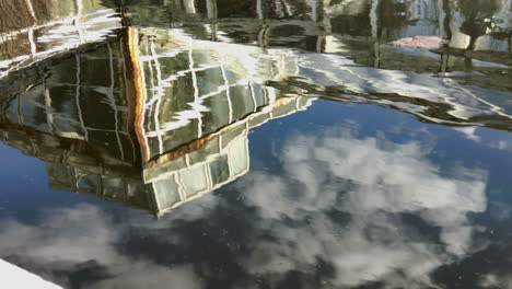 antiguo invernadero reflejo en un pequeño estanque